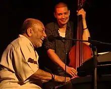 Eddie Palmieri performing in 2013 (left, with bassist Luques Curtis)