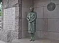 Statue of Eleanor Roosevelt in front of the United Nations logo.