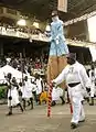 A performer on stilts as part of the Eyo Agere Molokun procession parading in the TBS.