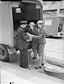 A police officer has his hand bandaged by women at the rear of an Austin K2/Y of the American Ambulance Great Britain following a V1 attack in Upper Norwood.