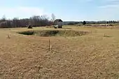 A picture of the Fort Dobbs site, which is primarily composed of several mounds of earth and a central excavation pit