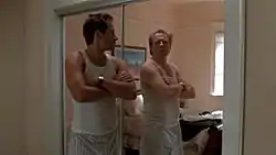 A man looks at himself in a mirror, seeing a completely different man's reflection.