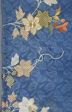 Rinzu (figured silk) dyed with a blue ground and patterns including shibori (tie-dyed) dots, plus gold embroidery.