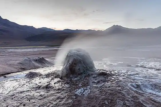 The vent is a small cone surrounded by steam in an unvegetated landscape