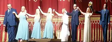 Modern costuming shown in closing bows following Götterdämmerung in 2013 at the Bavarian State Opera. Left to right: Gunther, the Rhinemaidens, Gutrune, Hagen, Brünnhilde, Siegfried
