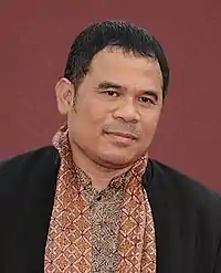 A man, on a red background, looking forward