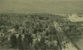 Sketch of Georgetown, Demerera, British Guiana showing  the town on the left, people and horses walking on the main waterfront street, and the harbour on the right, filled with ships