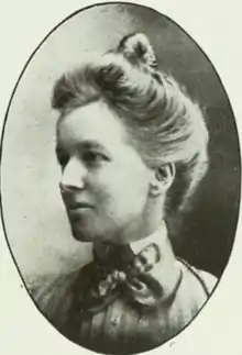 A white woman with fair hair dressed in a bouffant updo, wearing a high-collared striped blouse or dress, in an oval frame