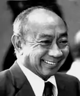 Black and white photograph of the head and shoulders of a balding Chinese man in a suit and tie, crying handsomely