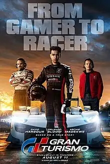 A young man stands in front of the front side of a car, which is surrounded by two other men standing on the left and right sides of it. The film's title and release date are centered at the bottom of the poster, with the tagline "From Gamer to Racer" centered at the top.