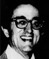 A grainy, black-and-white photo of a young white man looking at the camera with a smile.