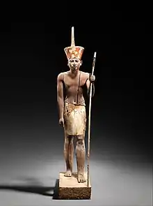 A guardian statue wearing the red crown which reflected the facial features of the reigning king, probably Amenemhat II or Senwosret II, and which functioned as a divine guardian for the imiut. Made of cedar wood and plaster c. 1919–1885 BC
