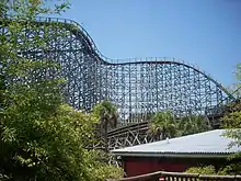 The lift hill of the lion track as it ascends 105.4&nbsp;ft (32.1&nbsp;m) and turns to the right towards the 91.8&nbsp;ft (28.0&nbsp;m) drop. Various pieces of track and tree foliage circumnavigate in the foreground.