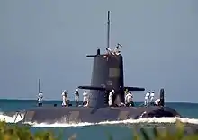 A submarine with people wearing white uniforms standing on the outer hull