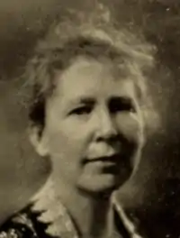 A middle-aged white woman wearing a collared jacket with lace trim