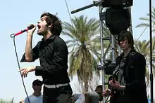 One man holding a microphone and a second man playing a guitar