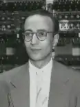Man with glasses standing in front of computational machines