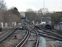 A pair of third-rail railway tracks are intersected by a second pair of tracks coming in from the right