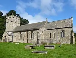 A stone church seen from the south with a battlemented tower on the left