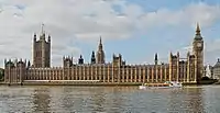 View of the long Parliament building, as seen from the southern bank of the Thames. On the left of the building is the Victoria Tower, flying the Union Flag; on the right is the Elizabeth Tower (often called Big Ben).
