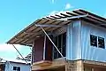 Hardwood purlins fixed to steel supports on a skillion roof and main roof. House under construction, tropical North Australia.
