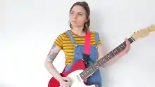 Blackery, with a tattooed arm, holding a guitar