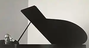 Stravinsky leaning his arm against a grand piano with its lid up