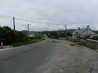 A long road, with stone walls and mountains in the background