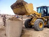 Iraqi Army engineers fill a section of four-foot HESCO MIL with a bucket loader.