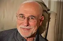 Portrait of Irvin Ungar, from the neck up, facing forward, wearing glasses and smiling slightly.