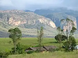 Two huts, wooded grasslands, and an escarpment with deep canyons