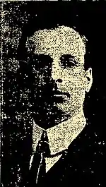 Black and white photo of a middle-aged man facing to the right, wearing a dark-coloured suit and a white dress shirt