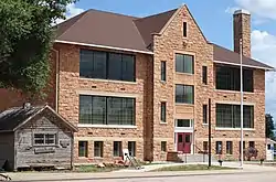Old wooden jail (left) and stone school building in Sundance