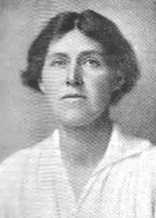 A white woman, her short dark hair center-parted, wearing a white blouse.