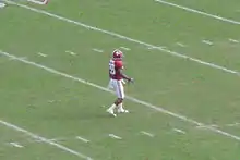 American football player waiting to field a punt on a green field.