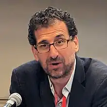 Eisinger seated at table speaking into microphone