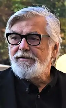 White-bearded Jiří Bartoška wearing glasses, looking to the right of the camera