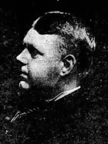 Middle-aged white man in profile; he has short hair, round cheeks, and a heavy brow