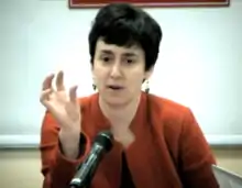 Cohen in a blazer sits and speaks