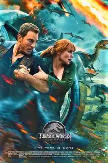 A man and a woman take cover behind a spherical vehicle, while various dinosaurs run from an erupting volcano.