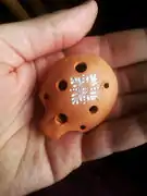 English pendant ocarina (unstrung, with two suspension holes) held in the hand.