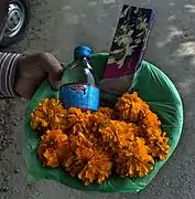 A typical basket of offerings, containing desi daru (country liquor), a pack of incense sticks and marigold flowers
