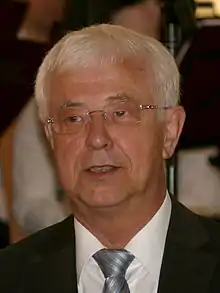 Image of an elderly man wearing a suit and a tie.