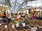 Vendors sell root vegetables at Gyeongdong Market, a crowded indoor mall with a glass roof