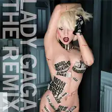 Lady Gaga naked with her right hand above her head and wearing a black glove on her left hand. Parts of her body are covered with thin stripes of newspaper.