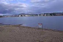 A metal sign erected on the sandy shores of the lake advises of the ban on water activity due to pollution