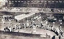 Black and white image of national teams marching into the stadium behind their national flag
