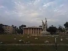 University buildings, with statue and scattered rocks