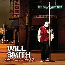 An image of a man wearing black jeans, a red and white varsity jacket, hat and sneakers, standing next to a directional street sign that point to "West Philly" and "Hollywood".