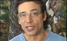 Luiz Carlos Vasconcelos wearing glasses, looking into camera while speaking
